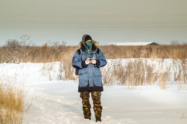 Mavi ceketli beyaz adam uzaktan kumandayla uçan bir dron fırlatıyor.