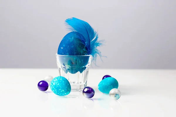 Uovo Pasqua Con Piuma Blu Portuovo Trasparente Tavolo Bianco — Foto Stock