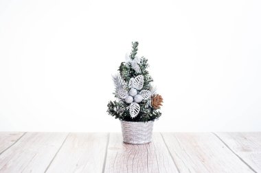 Beyaz arka plandaki ahşap masada şirin küçük Noel ağacı.