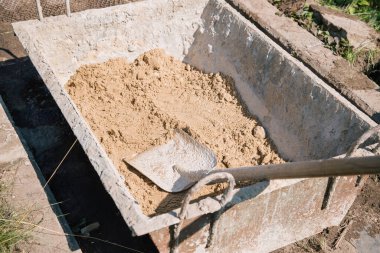 Bahçe yolu açmak için çimento karışımına kum yüklemek, bahçe arazisi inşaatı.