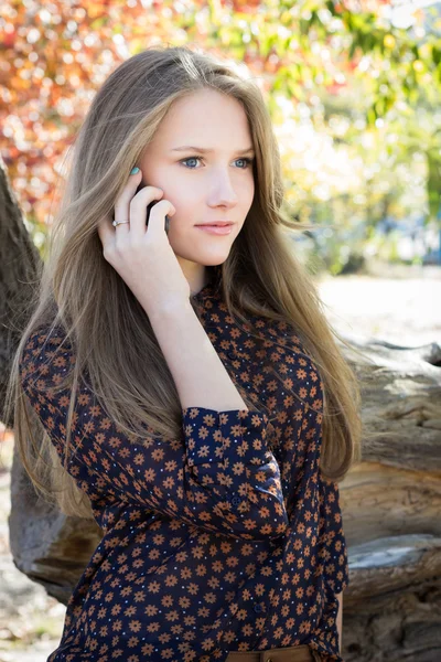 Giovane bella ragazza che chiama dal telefono cellulare nel parco — Foto Stock
