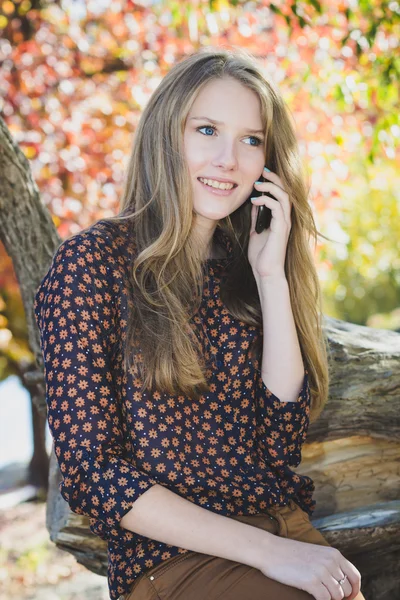 Young beautiful smiling girl talking on mobile phone in park — Stock Photo, Image
