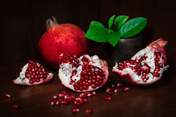Pomegranate with broken segments and leaves — Stock Photo, Image