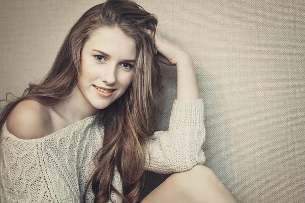 Joyful teenage girl sitting against neutral background and smiling — Stock Photo, Image