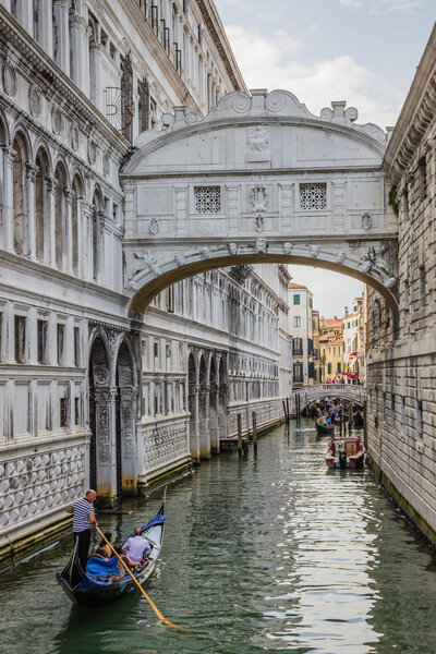 Venice, Italy - June 27, 2014: Tourists sailing on gondolas  on water canal under Bridge of Sighs