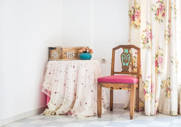 Vintage stijl interieur met tabel, gesneden stoel en bloemen gordijn Stockafbeelding