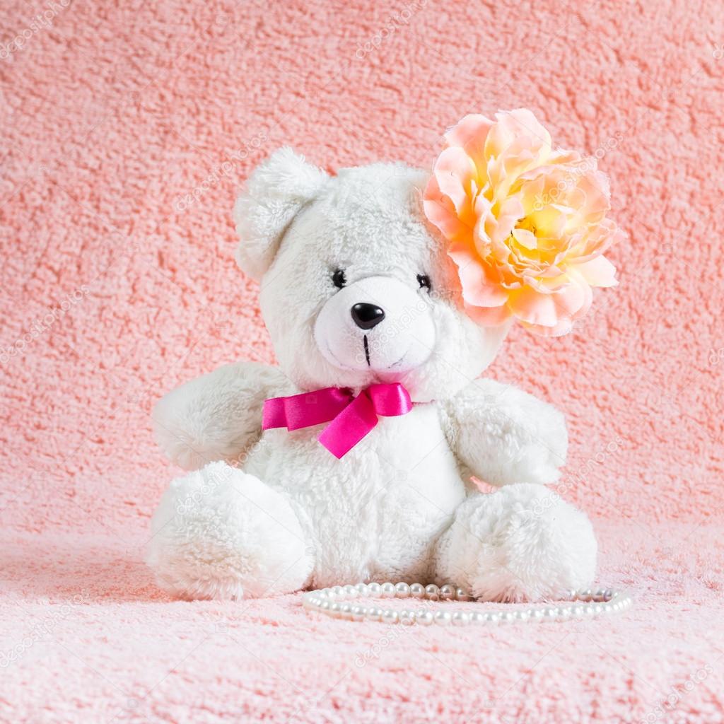 White teddy bear toy with orange flower barrette on head