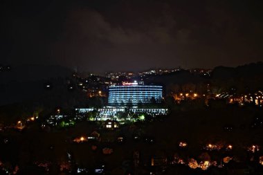 Geceleri karanlık fırtınalı bir gökyüzünün arka planında elektrikli aydınlatma olan binaların siluetleri