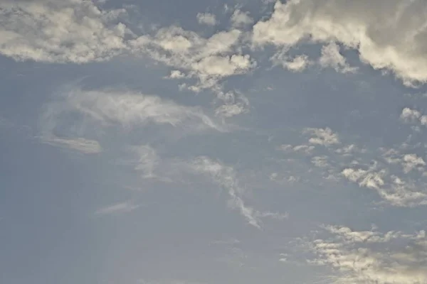 Light blue sky with light gray and white clouds in diffused light