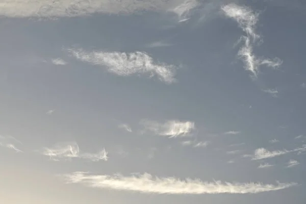 Light blue sky with light gray and white clouds in diffused light