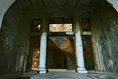 Klasik tarzda terk edilmiş eski bir taş binanın kemer ve sütunlarıyla ana giriş.
