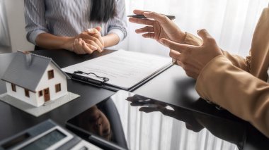 Emlakçı ve müşteri satın alma, sigorta ya da kredi alma ya da emlak ya da mülkiyet sözleşmesi hakkında tartışıyorlar.