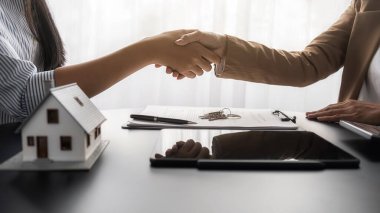 Emlakçı ve müşteriyle ev modeli satın alma, sigorta ya da kredi alma ya da emlak ya da mülkiyet sözleşmesi hakkında tartışıyor.