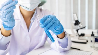 Bilim adamı, ilaç laboratuarındaki bir deney tüpünün içine bir numune bırakıyor. Yenilik Konsepti.