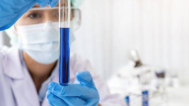 Bilim adamı ilaç laboratuvarında temiz çözeltiye sahip test tüpünü inceliyor..