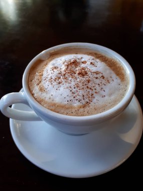 Tarafsız siyah masadaki bir kahve dükkanında köpüklü bir kapuçino.