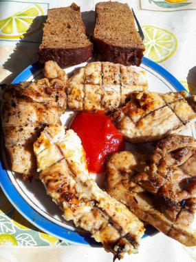 Izgara sulu tavuk eti ketçap ve tabakta ekmek. Izgarada et var. Barbekü.