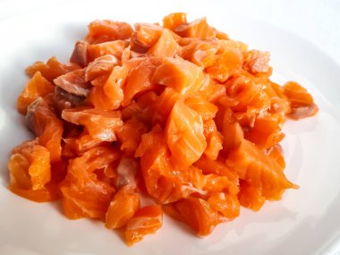 Beyaz arka planda küçük parçalar halinde kesilmiş taze ve çiğ somon filetosu.