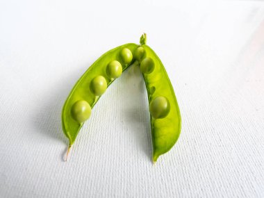 Yeşil bezelyeler beyaz arka planda parlak güneş ışığında izole edilmiş. Güzel ve detaylı botanik geçmişi