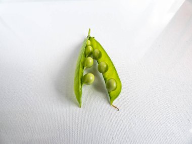 Yeşil bezelyeler beyaz arka planda parlak güneş ışığında izole edilmiş. Güzel ve detaylı botanik geçmişi