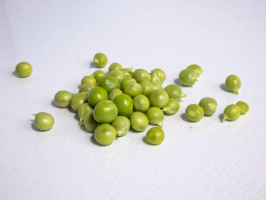 Bir avuç taze ve olgun bezelye, beyaz arka planda, parlak güneş ışığında izole edilmiş. Güzel ve detaylı botanik geçmişi