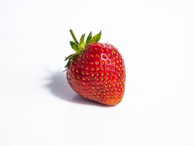 Taze ve olgun çilek beyaz, izole bir zemin üzerinde, parlak güneş ışığında, bir gölgeyle. Güzel ve detaylı botanik geçmişi