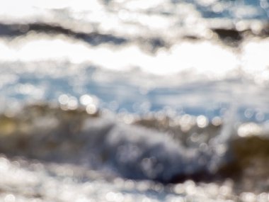 Dalgaların yumuşak mavi, beyaz ve kahverengi bokeh etkisi ve kasten okyanus manzarasının bulanık görüntüsü. Su tonlarında fotografik bokeh etkisi olan bulanık arkaplan
