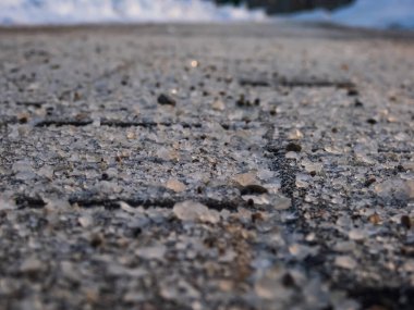 Kışın buz gibi kaldırım yüzeyinde tuz taneleri. Yolları açık tutmak için tuz uygulamak ve kış mevsiminde insanları buzdan ve kardan korumak, yakın görüş.