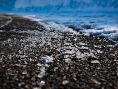 Macro shot of salt grains on icy sidewalk surface in the winter. Applying salt to keep roads clear and people safe in winter weather from ice or snow, closeup view clipart
