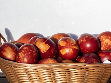 Doğal bitkilerle süslenmiş Paskalya yumurtaları ve çiçek çiçekleri ve dokuma sepetinde kaynatılmış soğan kabukları. Kahverengi yumurtaların üzerinde bitki deseni oluşturmanın geleneksel yolu