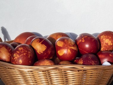 Doğal bitkilerle süslenmiş Paskalya yumurtaları ve çiçek çiçekleri ve dokuma sepetinde kaynatılmış soğan kabukları. Kahverengi yumurtaların üzerinde bitki deseni oluşturmanın geleneksel yolu