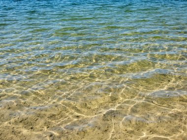 Kristal berrak ışık dokusu Mavi, yeşil ve turkuaz şeffaf su, ince beyaz kum tabanlı ve suda güneşin parlak yansıması.