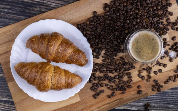 木製の板の上にコーヒーを飲みながらクロワッサン — ストック写真