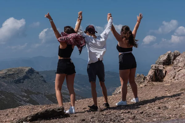 Kollarını bir dağın tepesine kaldırmış genç insanlar.