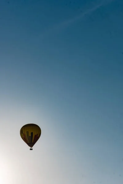 Sıcak hava balonu şafakta mavi gökyüzünde uçuyor.