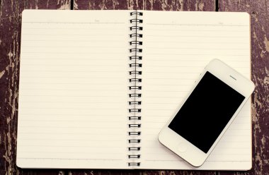 Akıllı telefon ile siyah perde beyaz ve açık defter eski dir