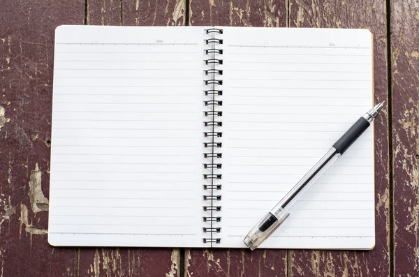 Cuaderno abierto y bolígrafo negro sobre fondo de madera sucio viejo — Foto de Stock