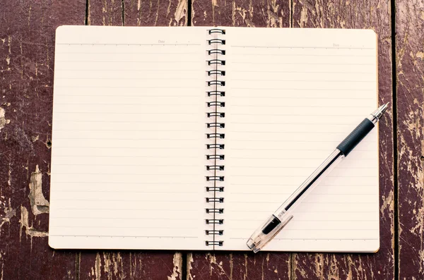 Cuaderno abierto y bolígrafo negro sobre fondo de madera sucio viejo — Foto de Stock