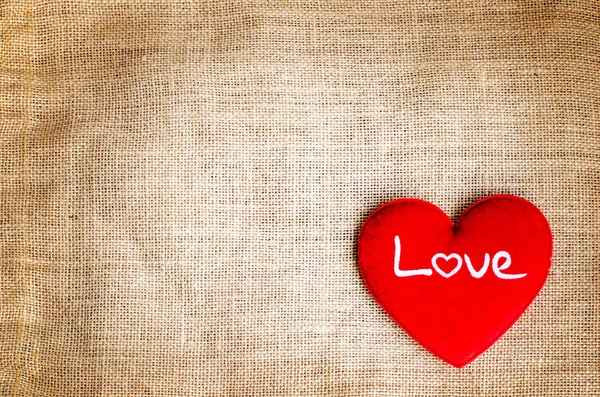 Red heart with love text on gunny sackcloth texture background — Stock Photo, Image