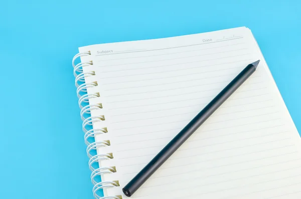 Caderno aberto com lápis sobre fundo azul — Fotografia de Stock