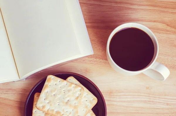 Tom öppen bok med kopp kaffe och kex på träbord - — Stockfoto