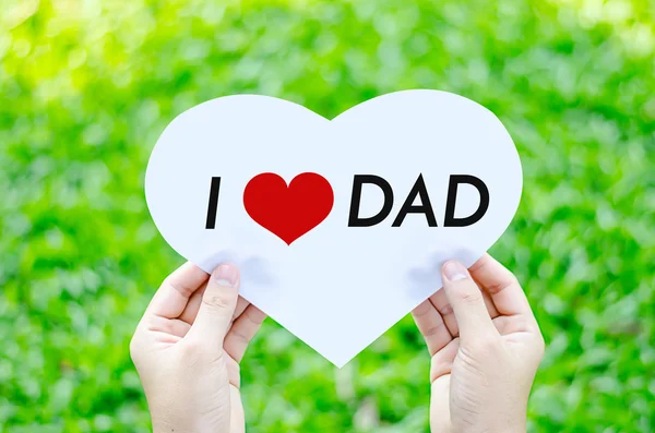 Mano sosteniendo papel de corazón blanco con me encanta papá texto en desenfoque gree —  Fotos de Stock