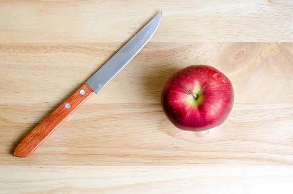 Manzana roja y cuchillo en mesa de madera — Foto de Stock
