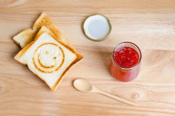 Engarrafamento de morango e pão torrado com marca de queimadura sorridente — Fotografia de Stock