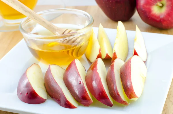 Яблоко с медом на тарелке на деревянном столе - Еврейский Новый год — стоковое фото