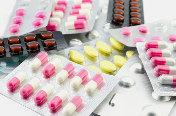 Капсулы и таблетки упакованы на белом фоне
