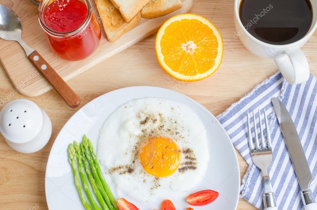 Healthy breakfast with fried egg, toasts and strawberry jam on w