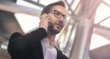 Takım elbise ve havaalanında telefonda konuşan gözlük yakışıklı işadamı portresi