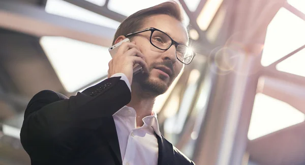 Portrait of handsome businessman in suit and eyeglasses speaking on the phone in airport — Stock Photo, Image