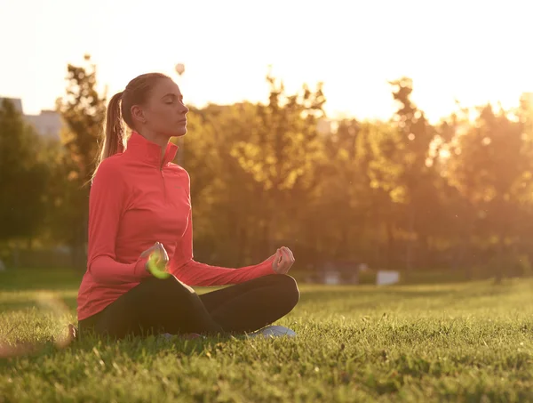 Młoda kobieta praktyki jogi na wschód słońca w parku — Zdjęcie stockowe